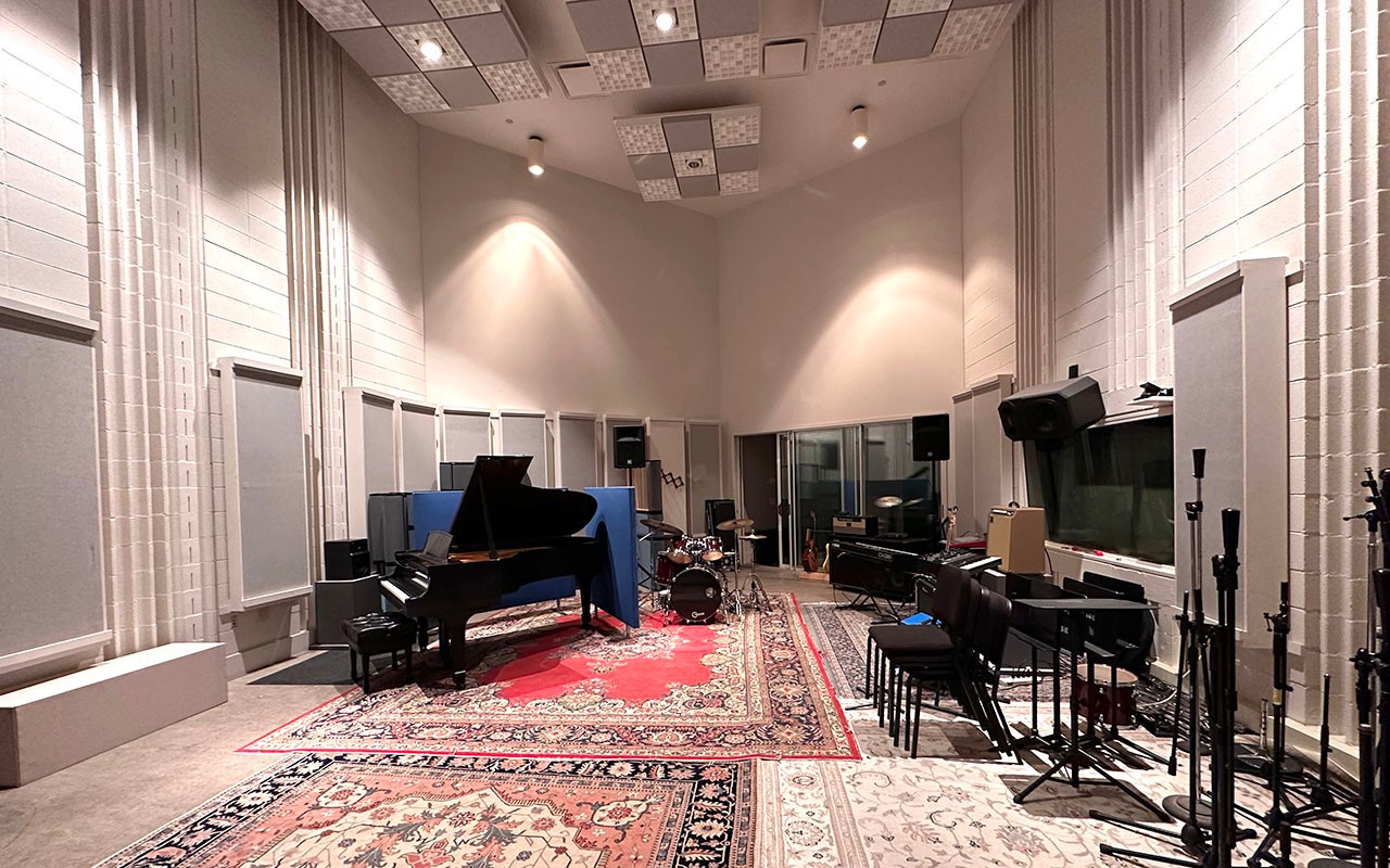 A recording space within the Ralph J. Corbett Audio Production Center outfitted with a piano and drum kit