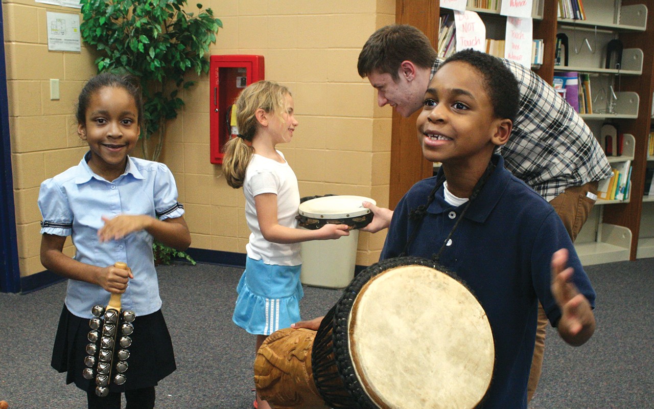 A music Education student interacts with primary aged children using percussion instruments