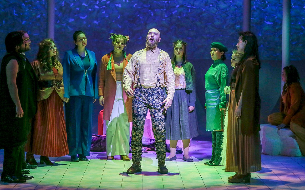 CCM voice students stand in a circle around a performer during a performance of the Cunning Little Vixen