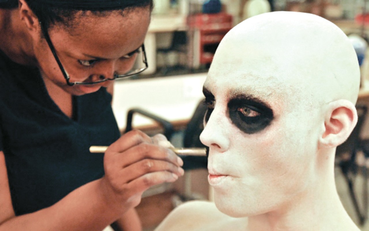Student applies ghostly make-up to a performer before Blood Wedding