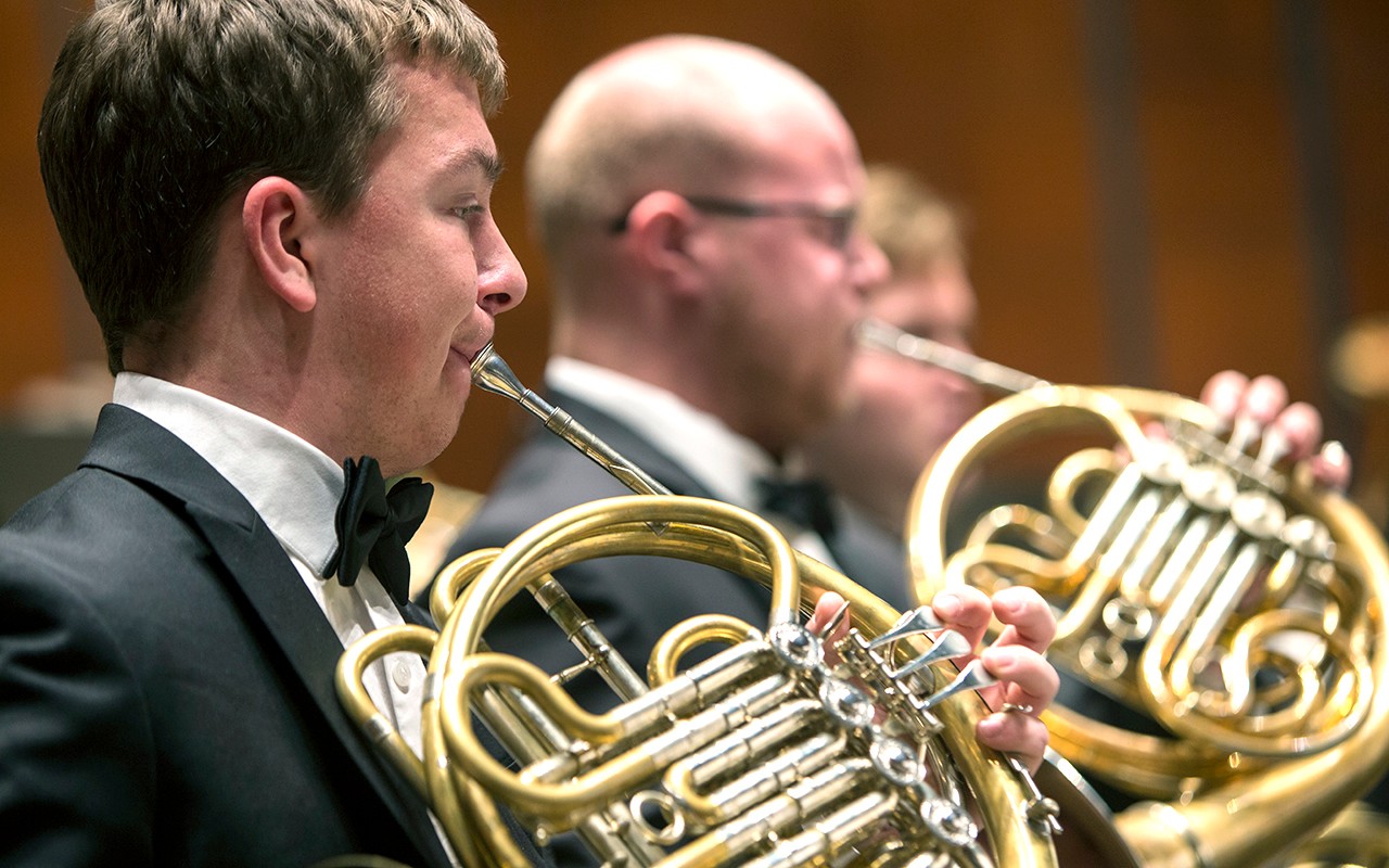Male french horn students perform with the wind ensemble in Corbett Auditorium
